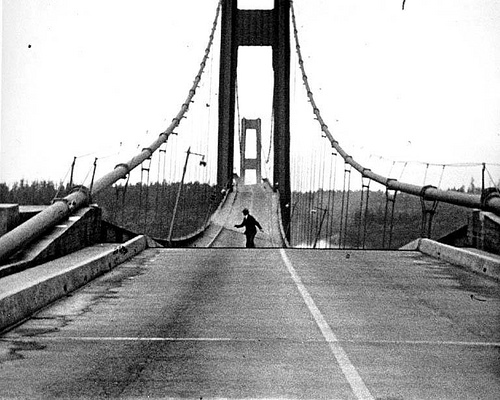 An old black and white photo of a man skateboarding across a bridge, showcasing his skills.