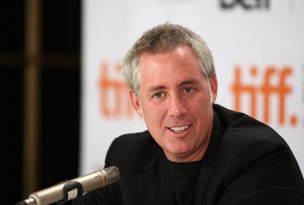 A man smiling at a microphone during a podcast recording.