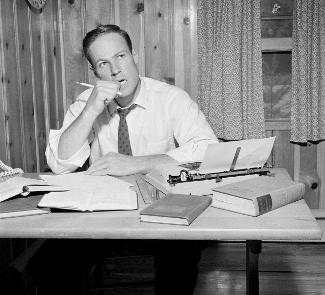 A man sitting at a desk with a typewriter.