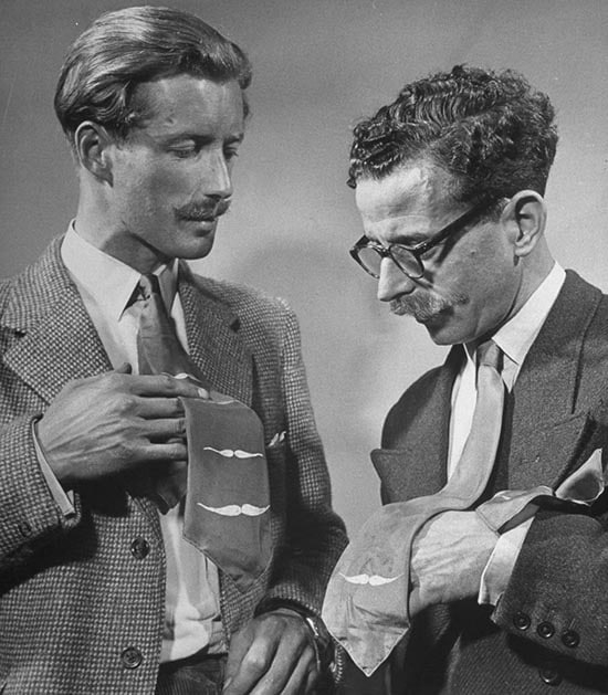 Two men are admiring each other's ties, noticing the minor differences.
