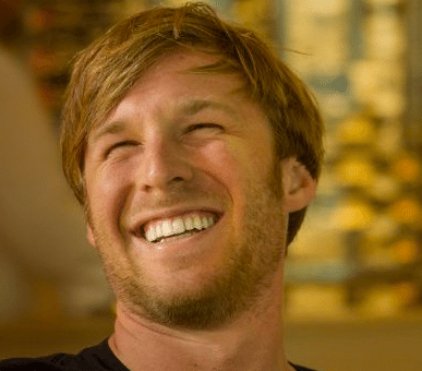 A man sits in a bar, smiling.