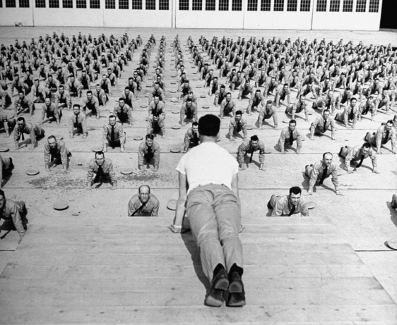 A man is demonstrating essential leadership qualities to a large group of people.