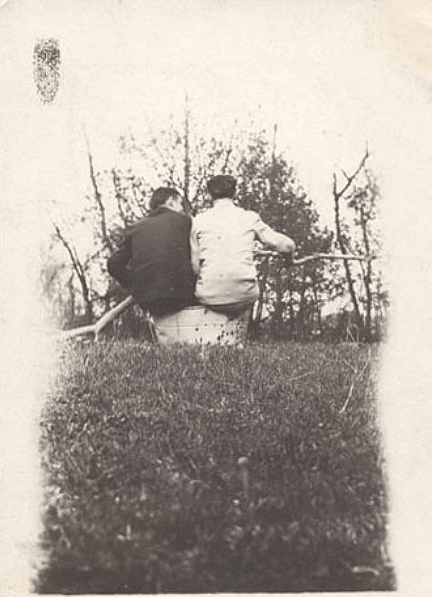 An old photo of two people sitting in a field.
