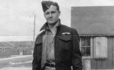A man in a military uniform standing confidently in front of a house.