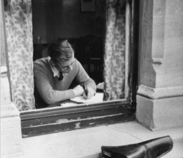 A man in a window, twenty-one old, writing.