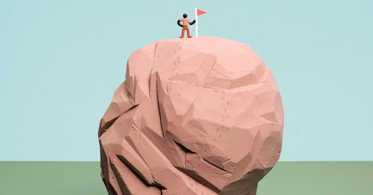 A man standing on top of a rock with a flag.