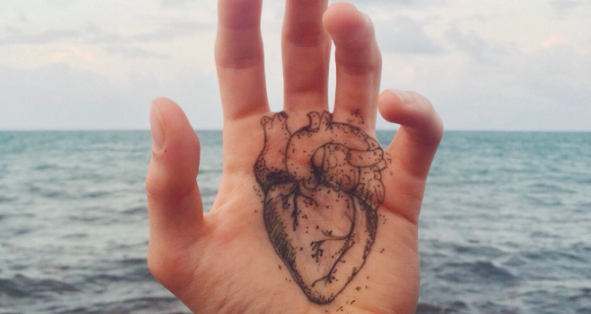 A person's hand with a heart drawn on it, symbolizing emotion.