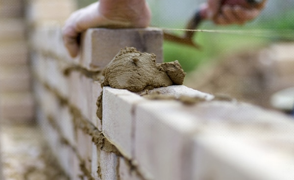 Bricklayer motivated by personal growth, applying mortar to lay bricks.